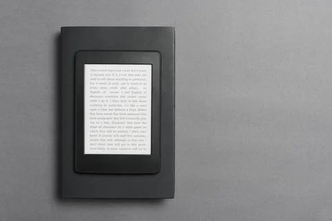 Electronic reader over a closed black traditional book, on a gray background. Stock Photos