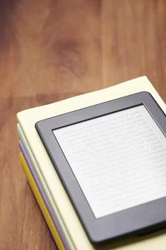 Electronic reader with a text on the screen on a stack of books on a wooden desk Foto stock