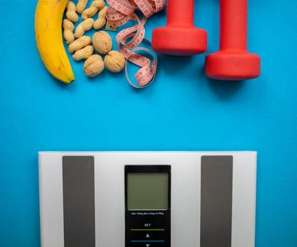 Electronic scale, banana, nuts, measuring tape and red dumbbells Stock Photos