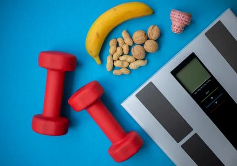 Electronic scale, nuts, banana, measuring tape and red dumbbells Stock Photos