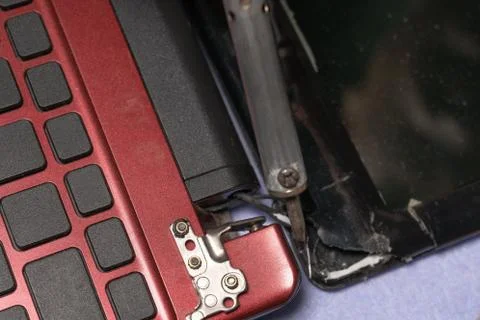 Electronic technical support concept - soldering iron on broken laptop displa Stock Photos