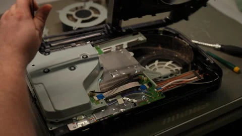 Electronic technician carefully disassembling game console motherboard in repair Stock Footage 306892120
