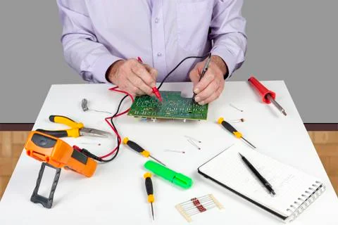 Electronic test engineer using a multimeter to test a curcuit board Stock Photos
