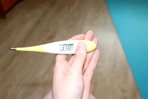 Electronic thermometer in a woman's hand with elevated, subfebrile temperatur Stock Photos