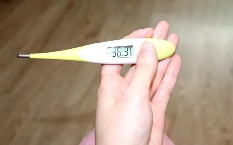 Electronic thermometer in a woman's hand with normal temperature on the scree Stock Photos