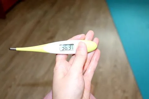 Electronic thermometer in a woman's hand with normal temperature Stock Photos