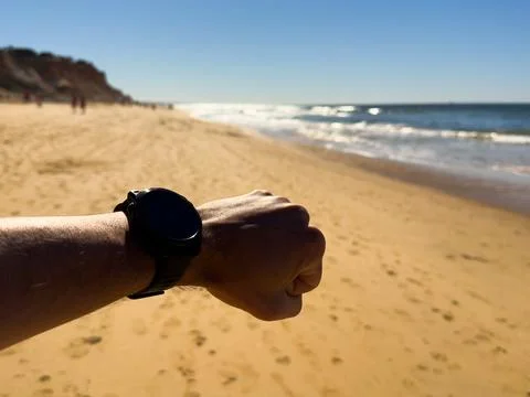 Electronic watch with blank white display on hand against sea background. A.. Stock Photos
