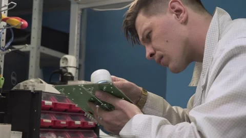 An electronics engineer examines a circuit board through a magnifying glass. Stock-Footage 332532934