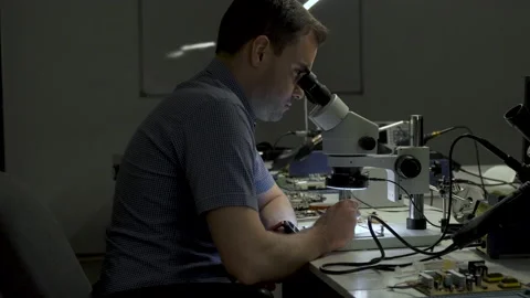 Electronics engineer is soldering an electric board with processors in a office Stock Footage 133000736