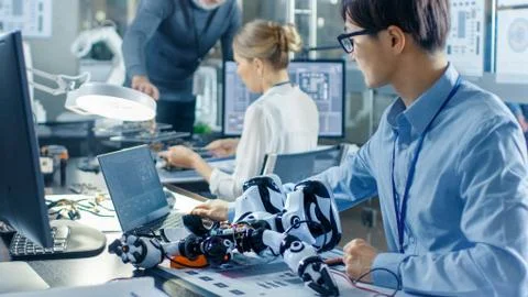 Electronics Engineer Works with Robot, Manipulating its Responses and Checkin Stock Photos