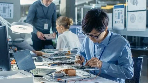 Electronics Engineer Works with Robot, Soldering Wires and Circuits. 写真素材