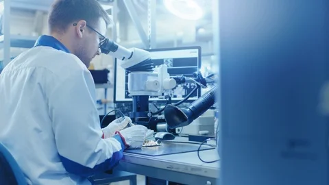 Electronics Factory Worker in White Work Coat Soldering a Printed Circuit Board Stock Footage 98726881