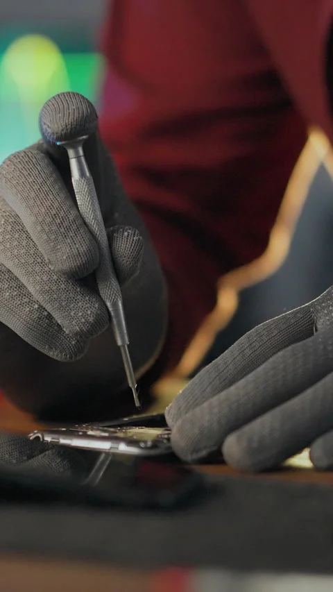 An electronics mechanic in a workshop repair shop grips a screwdriver unscre Stock Footage 341283913