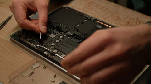 Electronics repair professional carefully disassembling laptop motherboard Stock Footage 301401241