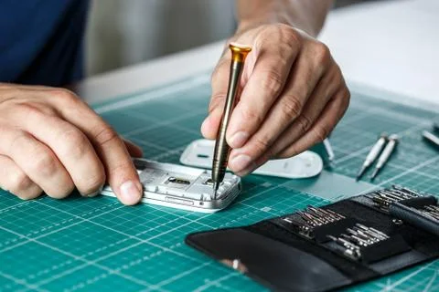 Electronics repair service. Technician disassembling smartphone for inspecting. Stock Photos