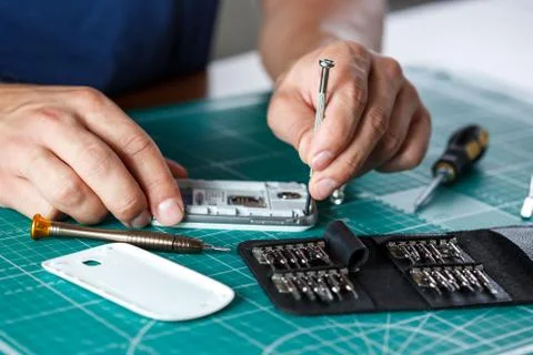 Electronics repair service. Technician disassembling smartphone for inspecting. Foto stock