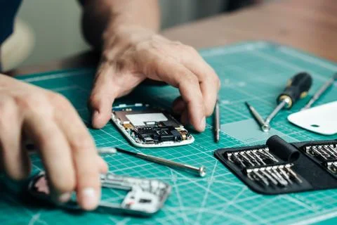 Electronics repair service. Technician disassembling smartphone for inspecting Stock Photos