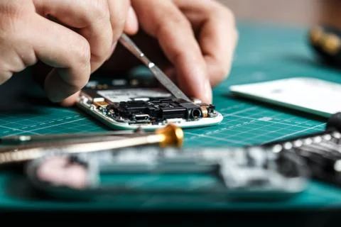 Electronics repair service. Technician disassembling smartphone for inspecting Stock Photos