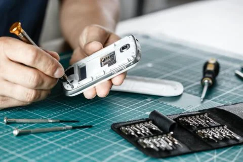 Electronics repair service. Technician disassembling smartphone for inspecting Stock Photos