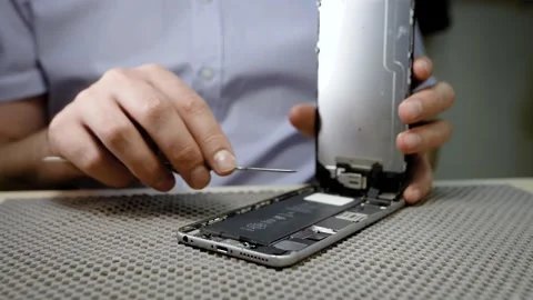 An electronics repairman repairs a broken smartphone, opens the phone Stock Footage 137658924