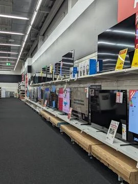 Electronics store aisle with wall mounted televisions and price signs on di.. Foto stock
