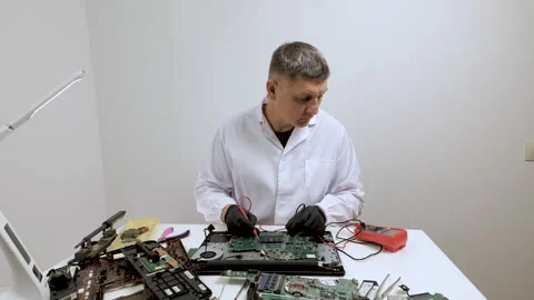 Electronics technician testing laptop motherboard at workbench Stockbeeldmateriaal 334389569