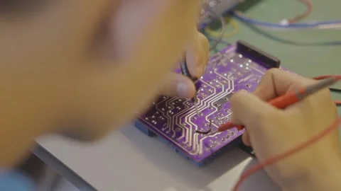 Electronics Technician Testing Purple Circuit Board with Multimeter Probes Stock Footage 336610083