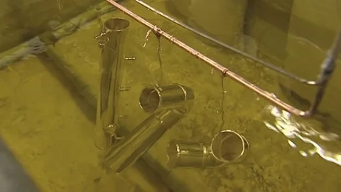 Electroplating process: silver coating brass elements in a dip bath Stock Footage 82335627