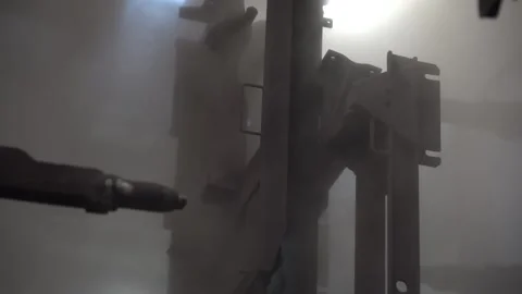 Electrostatic spray gun applying black powder onto a hanging steel bracket Video stock 346303263