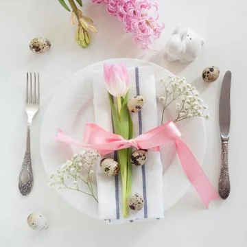 Elegance table setting with pink ribbon and tulip. Easter romantic dinner. Stock Photos