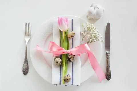 Elegance table setting with pink ribbon and tulip. Easter romantic dinner. Stock Photos