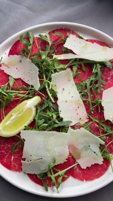 Elegant beef appetizer. Delicate sliced beef with fresh greens and lemon Stock Footage 335672219
