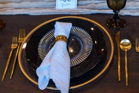 Elegant black table setting with gold accents, textured dinnerware Stock Photos