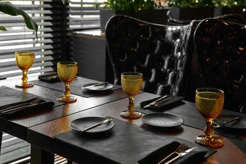 Elegant black table setting: plates, napkin and silverware over black background Stock Photos