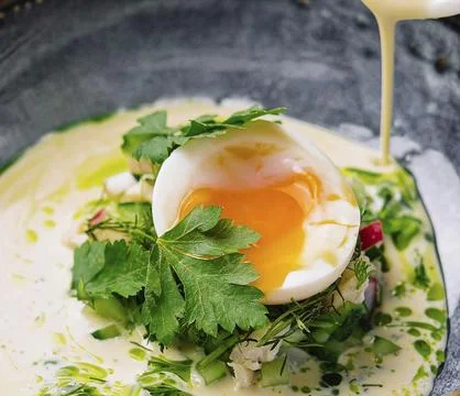 Elegant breakfast of poached egg with a drizzle of hollandaise sauce, garnished Stock Photos
