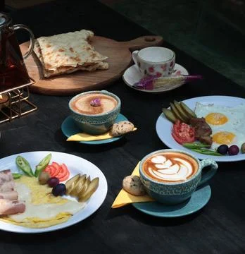 Elegant breakfast table featuring omelette, sliced pickles, olives, tomatoes Stock Photos