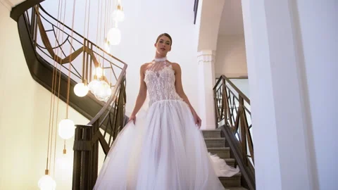 Elegant bride gracefully descends staircase in enchanting wedding photoshoot Stock Footage 321623701
