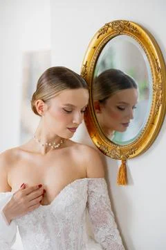 Elegant bride looking at reflection in ornate mirror Stock Photos