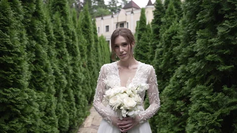 An elegant bride posed gracefully amid lush greenery, radiating charm and beauty Vidéo 291690780