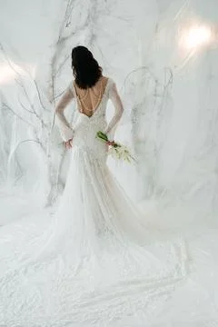 Elegant bride standing back to camera in a lace wedding dress with a bouquet. Foto stock
