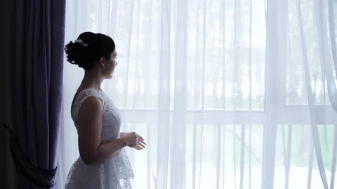 Elegant bride stands at the window and looks into the distance. Vidéo 106577053