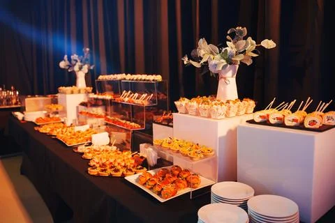 Elegant buffet spread featuring various appetizers and desserts at evening event Stock Photos