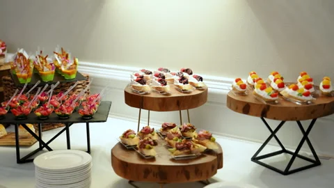 Elegant buffet table with assorted gourmet appetizers displayed on rustic wooden Stock Footage 322799898