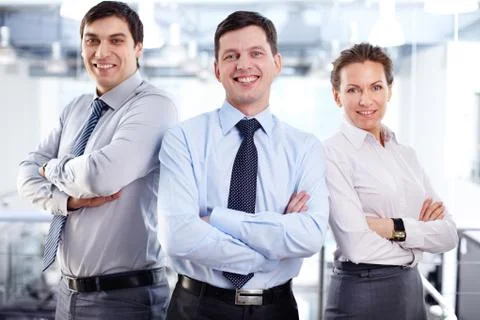 Elegant business team standing cross-armed expressing positivity and strong infl Stock Photos