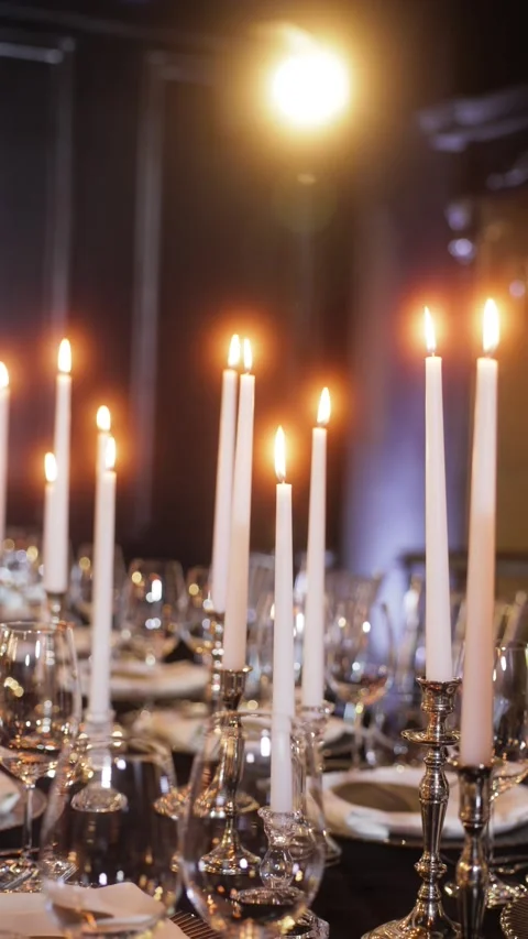 Elegant candlelight dinner setup with tall white candles in silver holders Stock Footage 320649324