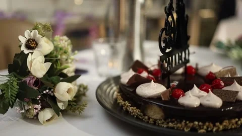 Elegant Close-up of Chocolate Cake and Bouquet on Decorated Celebration Table Stock Footage 340560645