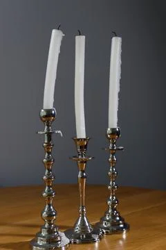 Elegant Collection of Three Silver Candlesticks with Long, White, Dripping Foto stock