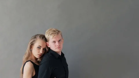 Elegant couple laughing for the camera while holding arm to arm. On grey 動画素材 79739334