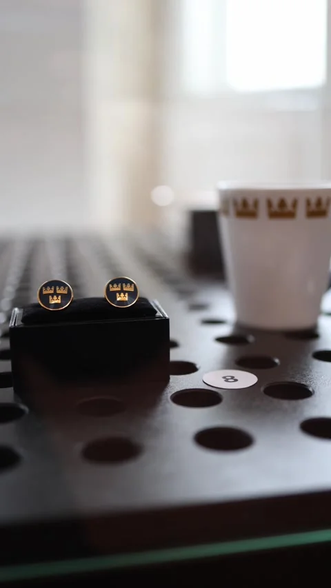 Elegant cufflinks with a crown emblem placed on a perforated surface, accompanie Stock Footage 301241207