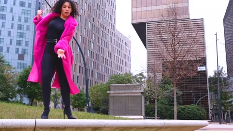 Elegant dancer in a pink coat performing artistic movements in an urban setting Stock Footage 306454766